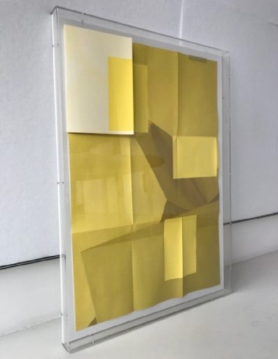 Lijst van plexiglas met geel kunstwerk.