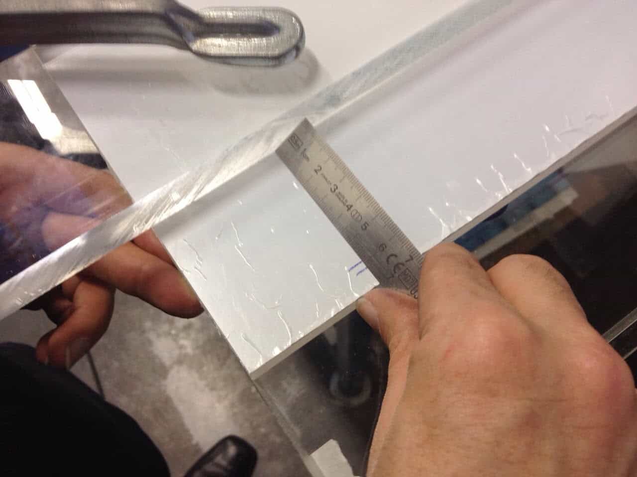 Alt: Hand meet de dikte van aluminiumplaat met een schuifmaat voor nauwkeurige fabricage.